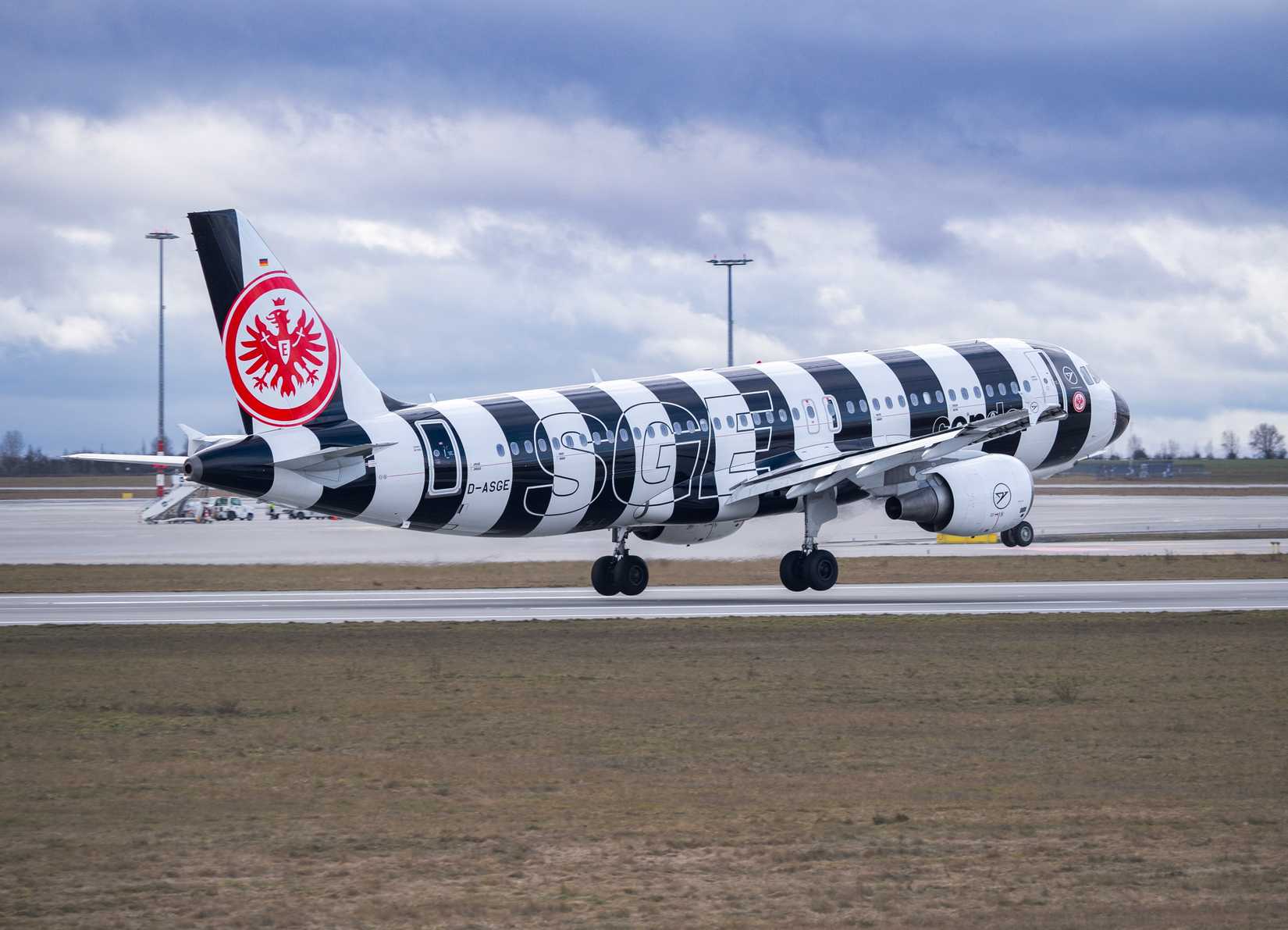 Condor Airbus A320 passenger airplane with black and white striped Eintracht Frankfurt special livery landing at airport.