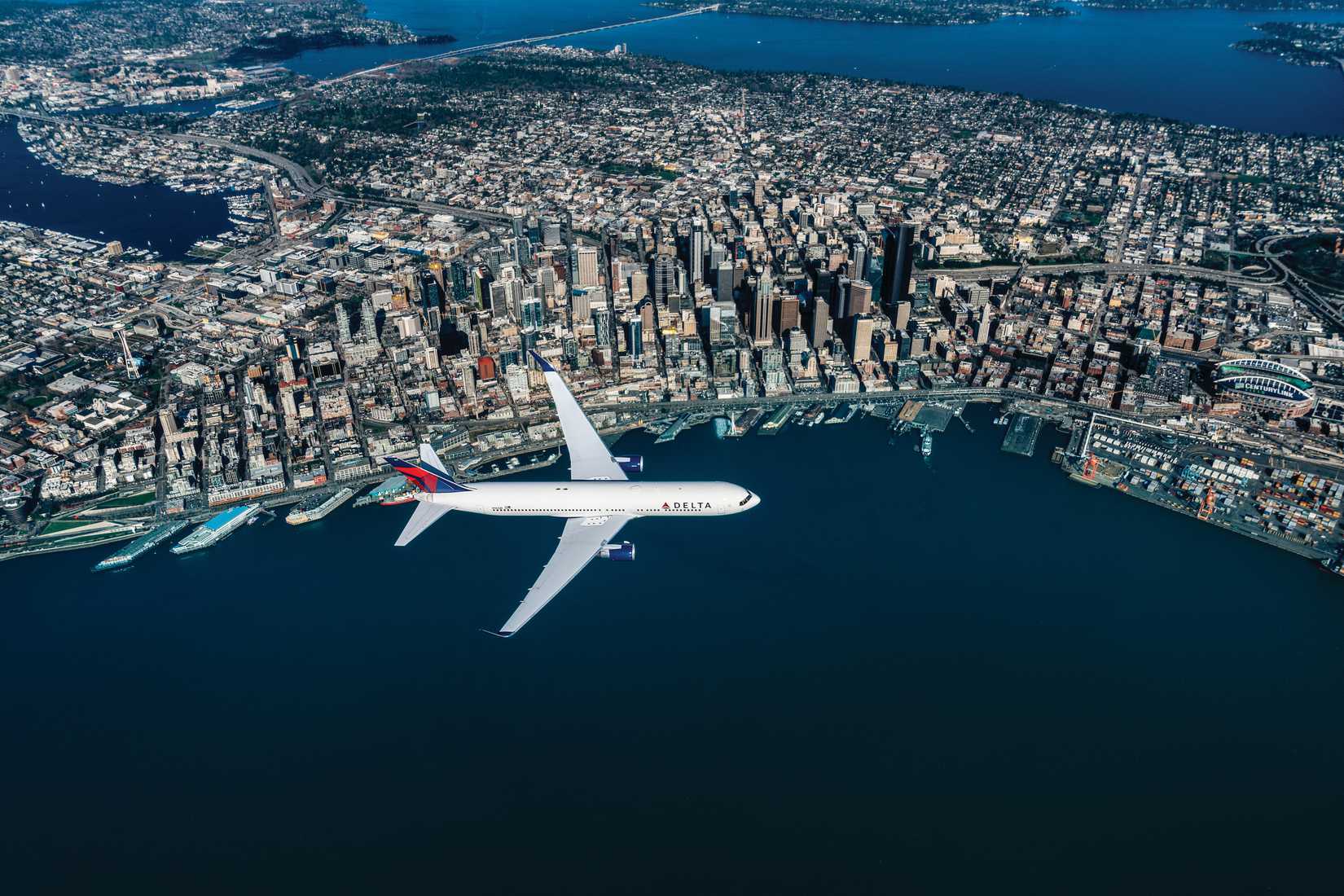 A Delta Air Lines 767-300 passenger jet flies over the Seattle skyline.