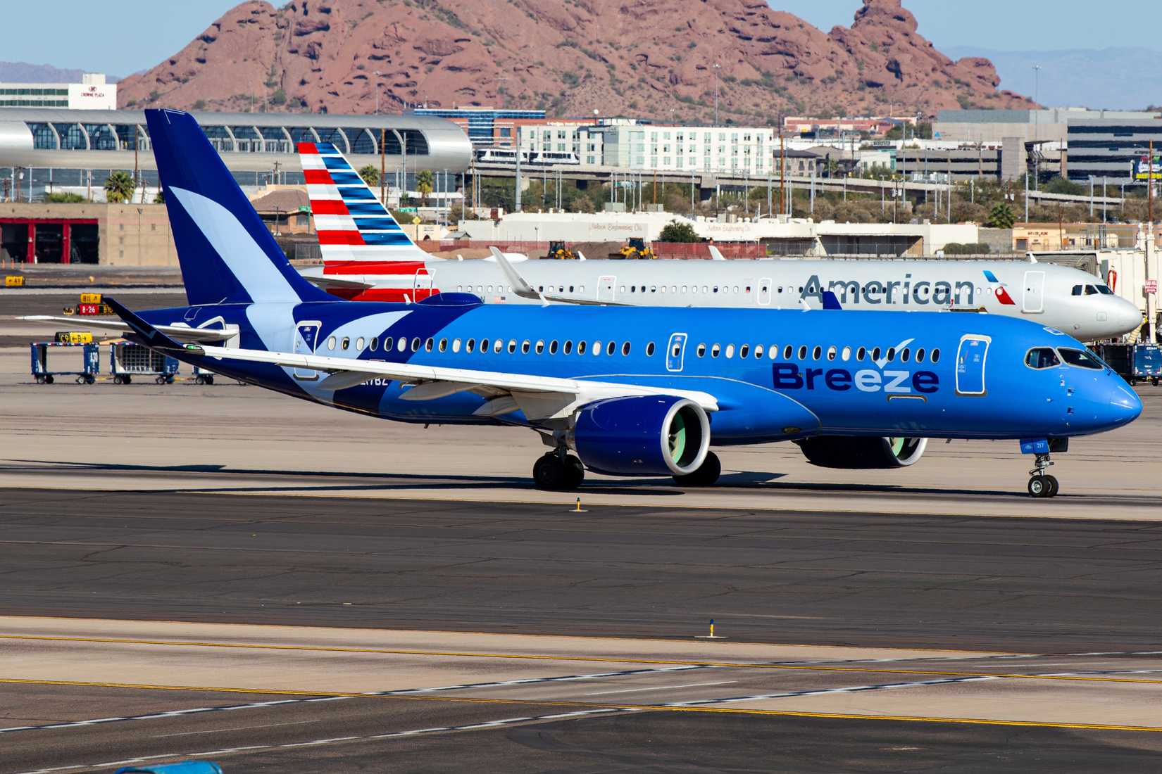 Breeze Airways Airbus A220-300 aircraft with American Airlines aircraft in the background