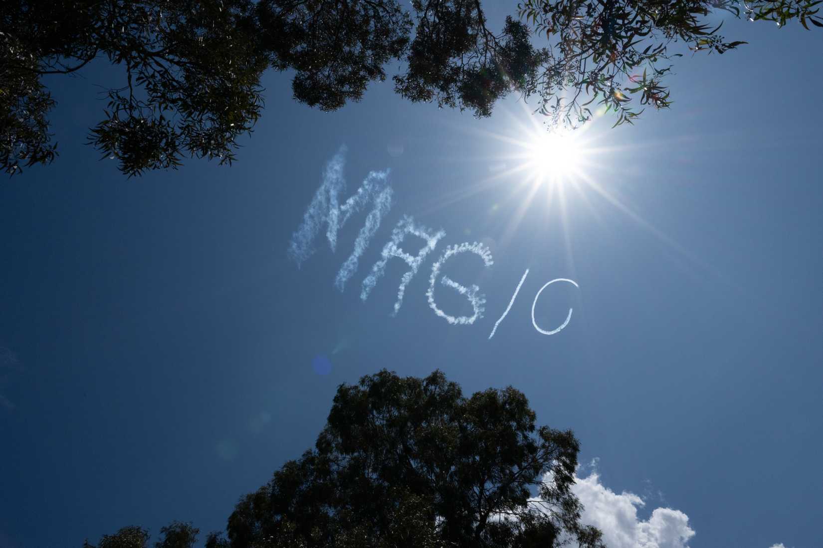 A striking image of the word "MAGIC" written in the sky with clouds of smoke, by an airplane performing skywriting. 