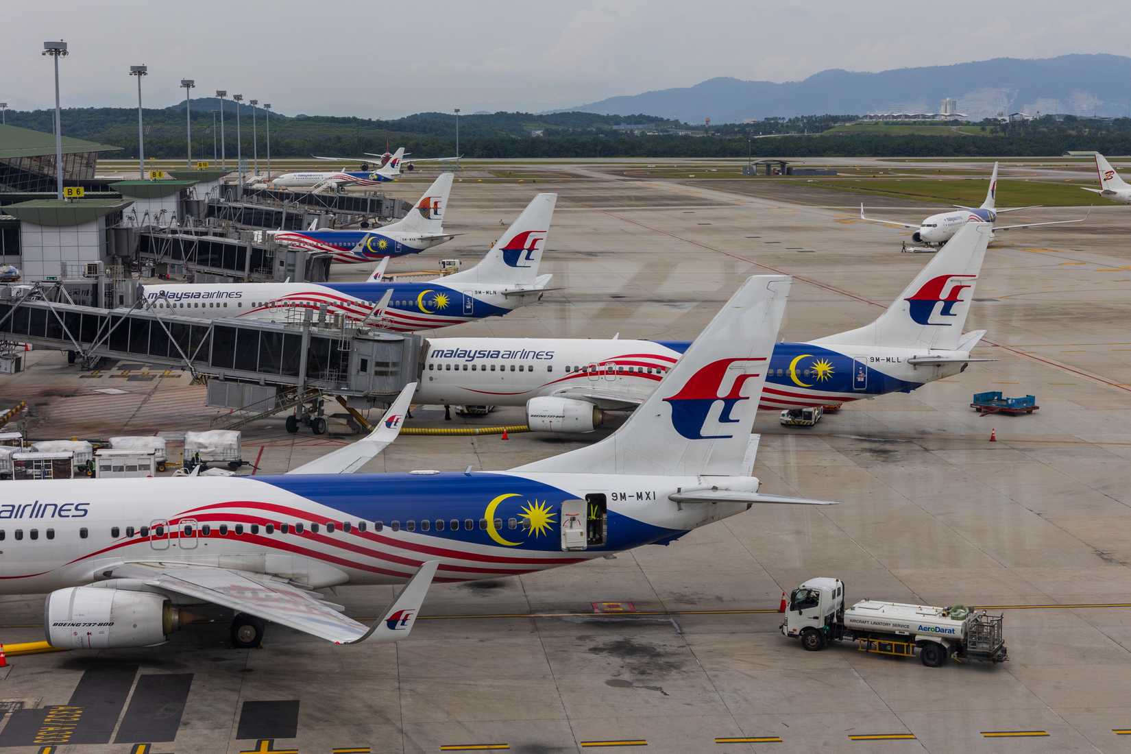 Several malaysia airlines boeing 737 airplanes parked at gates