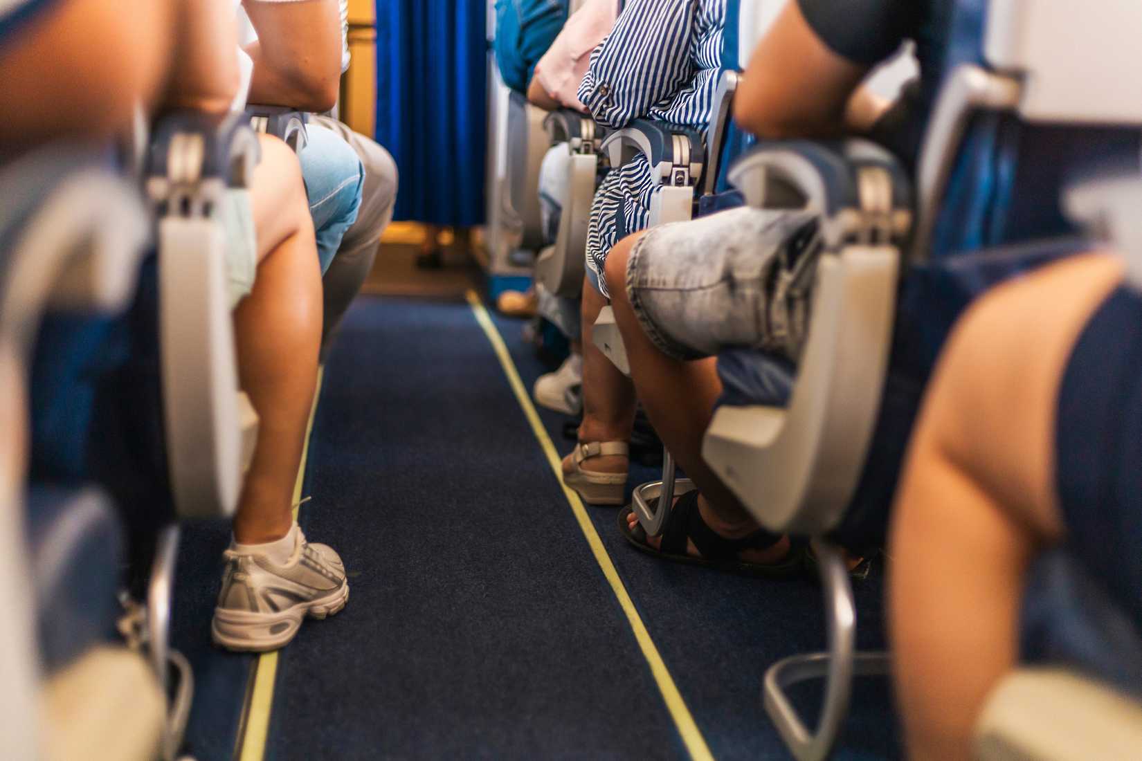 Antalya, Turkey - 14-07-2025: Travelers are seated in an airplane, with their legs visible from the aisle. The atmosphere indicates anticipation as the aircraft prepares for departure