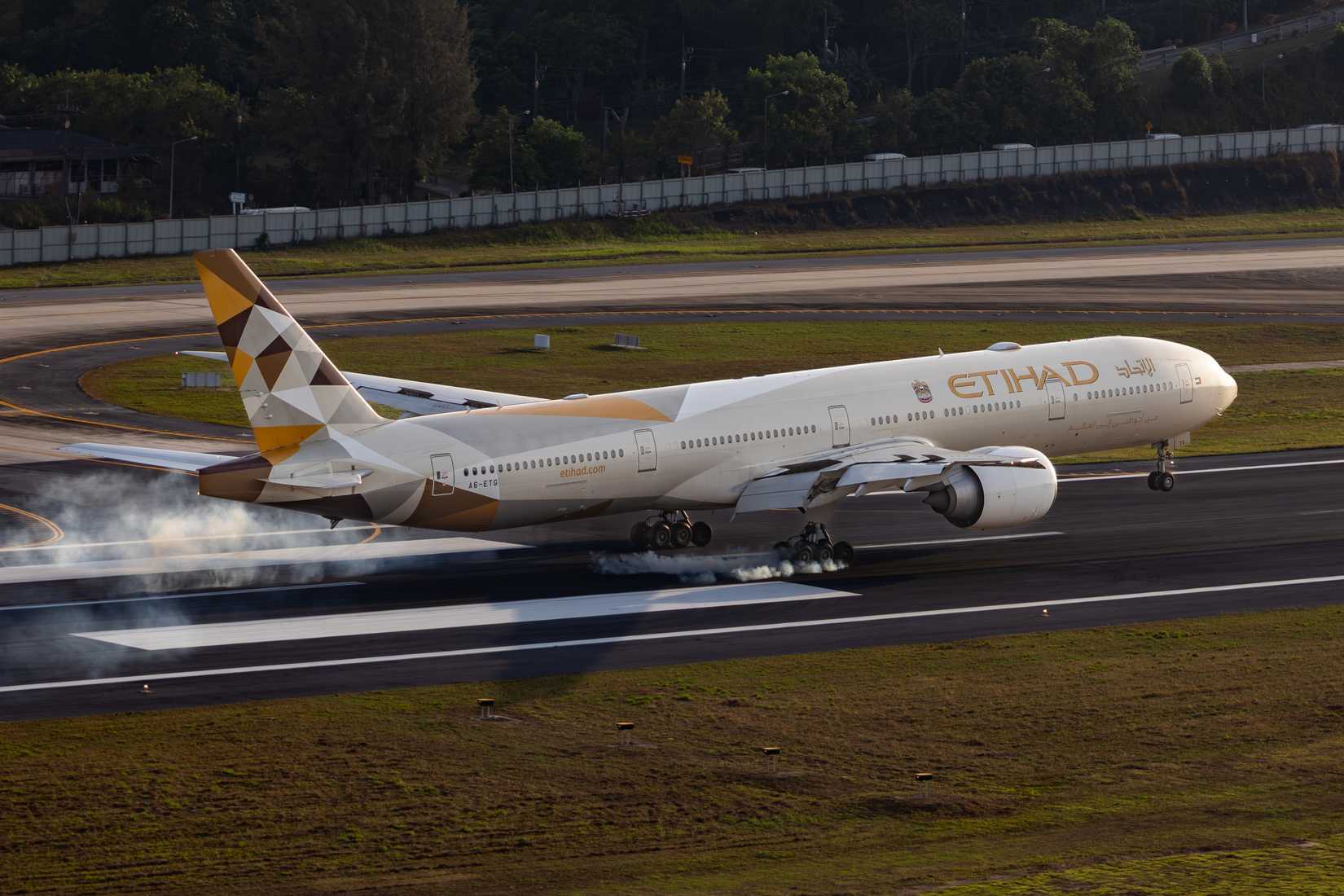 Phuket, Thailand – February 22, 2026: Etihad Airways Boeing 777 wide body passenger aircraft touching down on the runway with tire smoke during landing at Phuket International Airport.