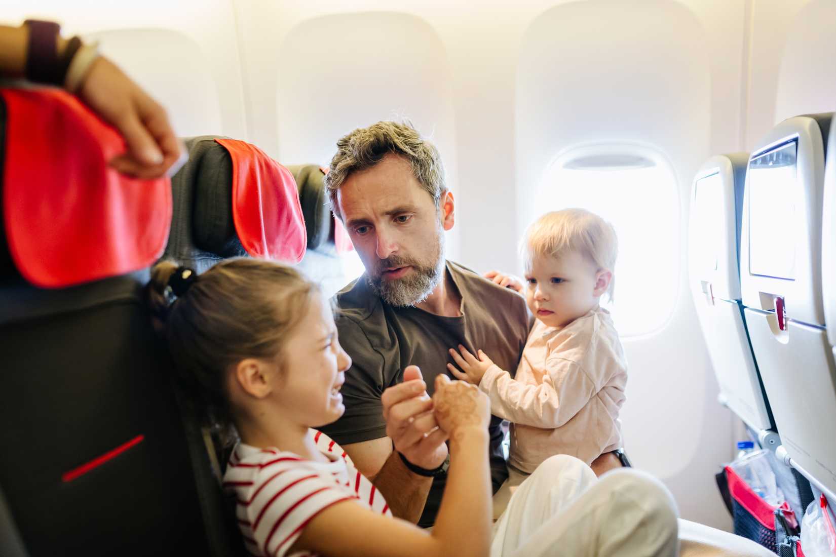 father with upset child and infant on airplane