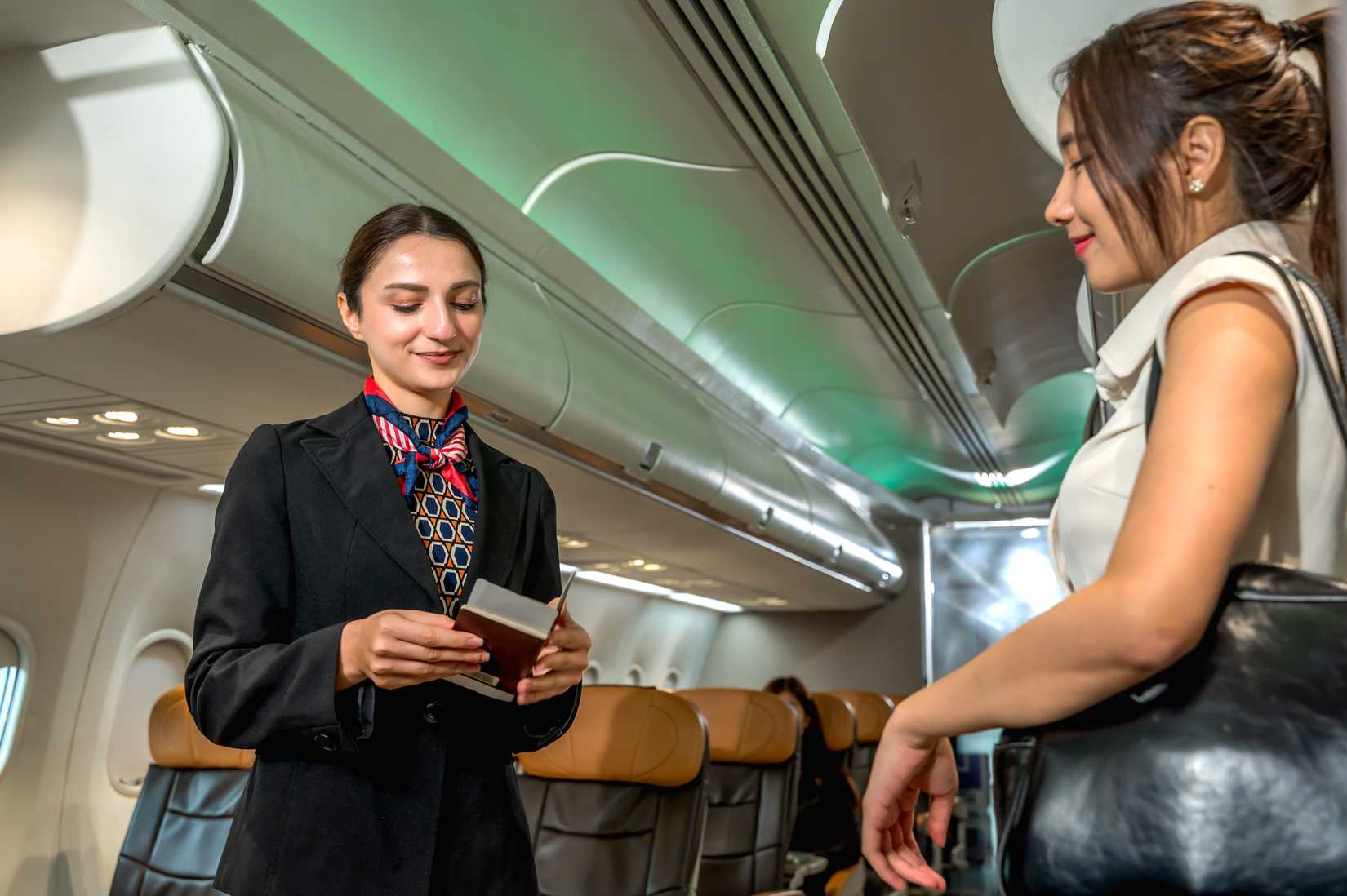 woman boarding aircraft with female flight attendant checking ticket