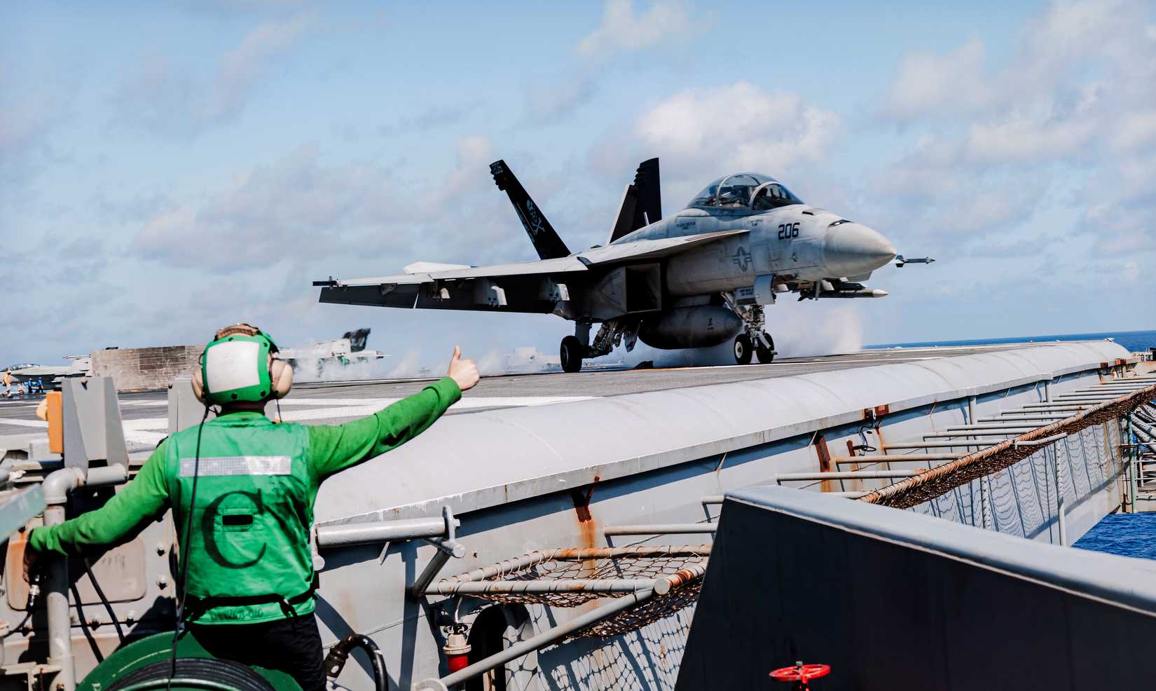 A close-up photo of an F-18 taking off from a carrier at sea, seconds before it leaves the flight deck.