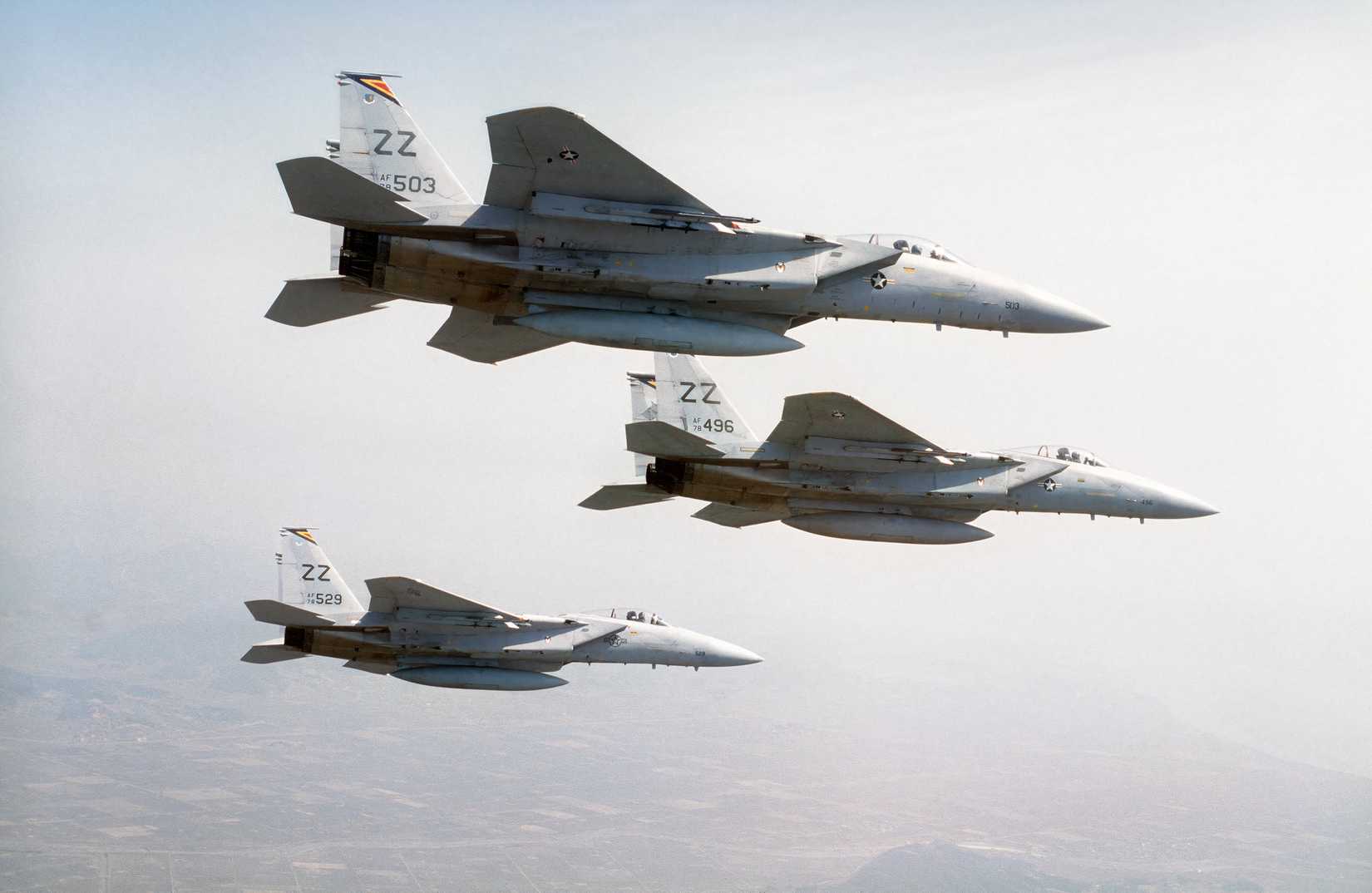 A photo displaying three F-15s flying in formation against a hazy background.