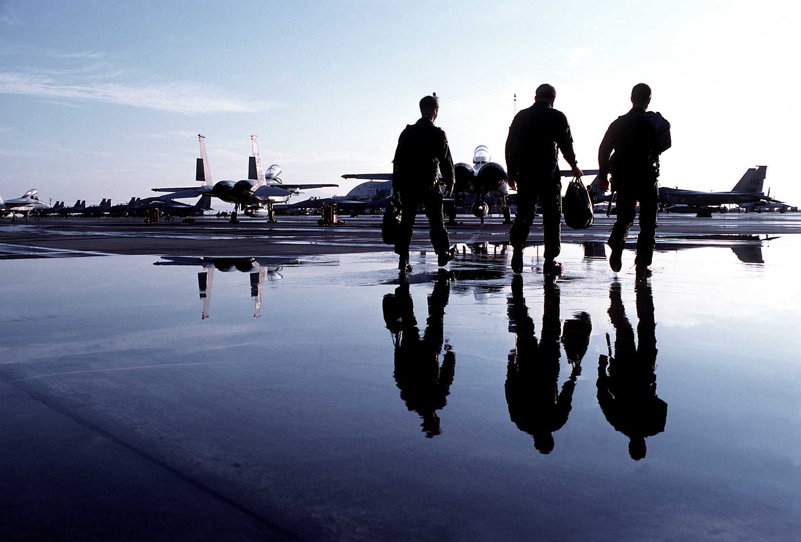 A photo showing three pilots walking towards parkedF-15s.