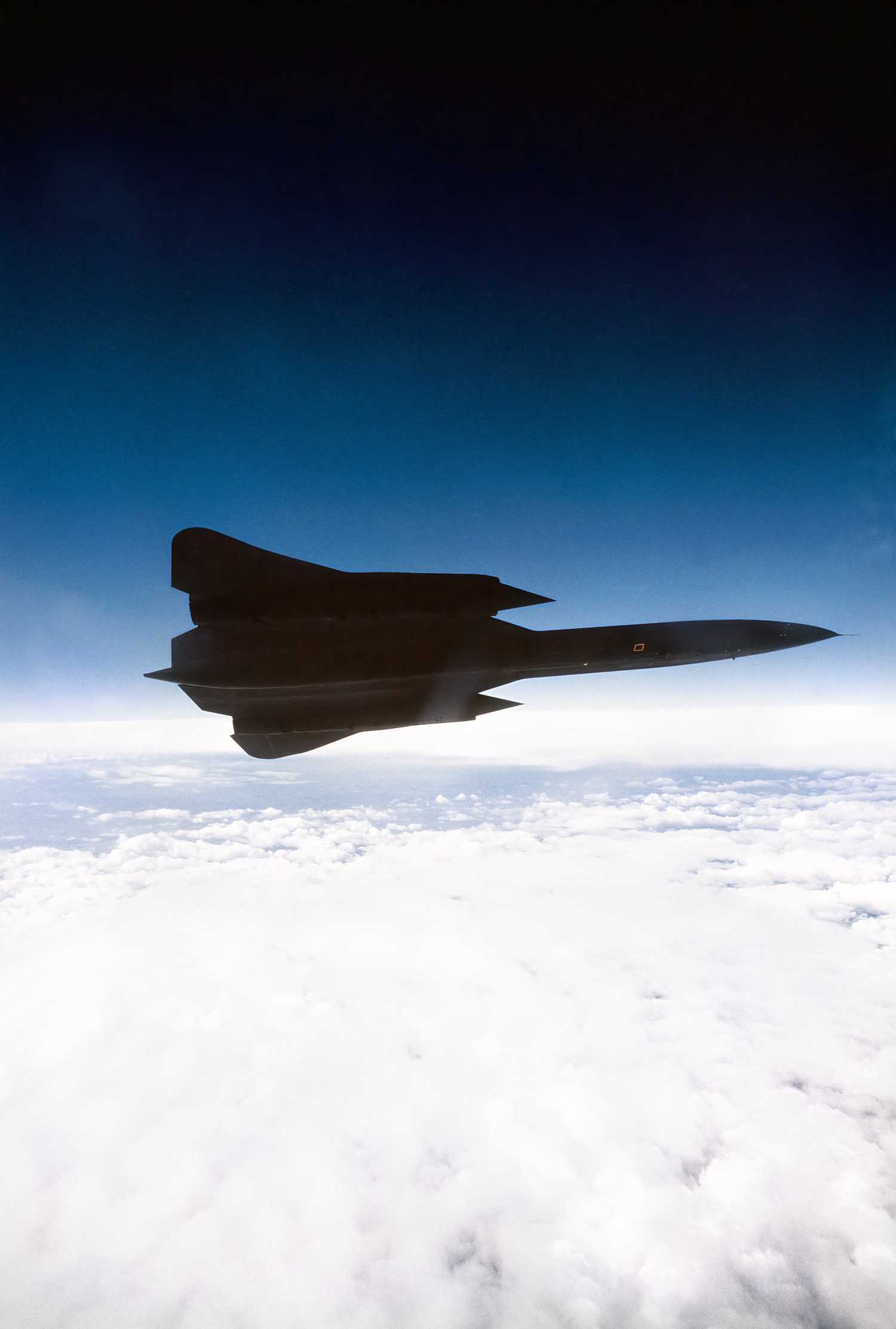 A photo of an SR-71 making a port side turn above the clouds.