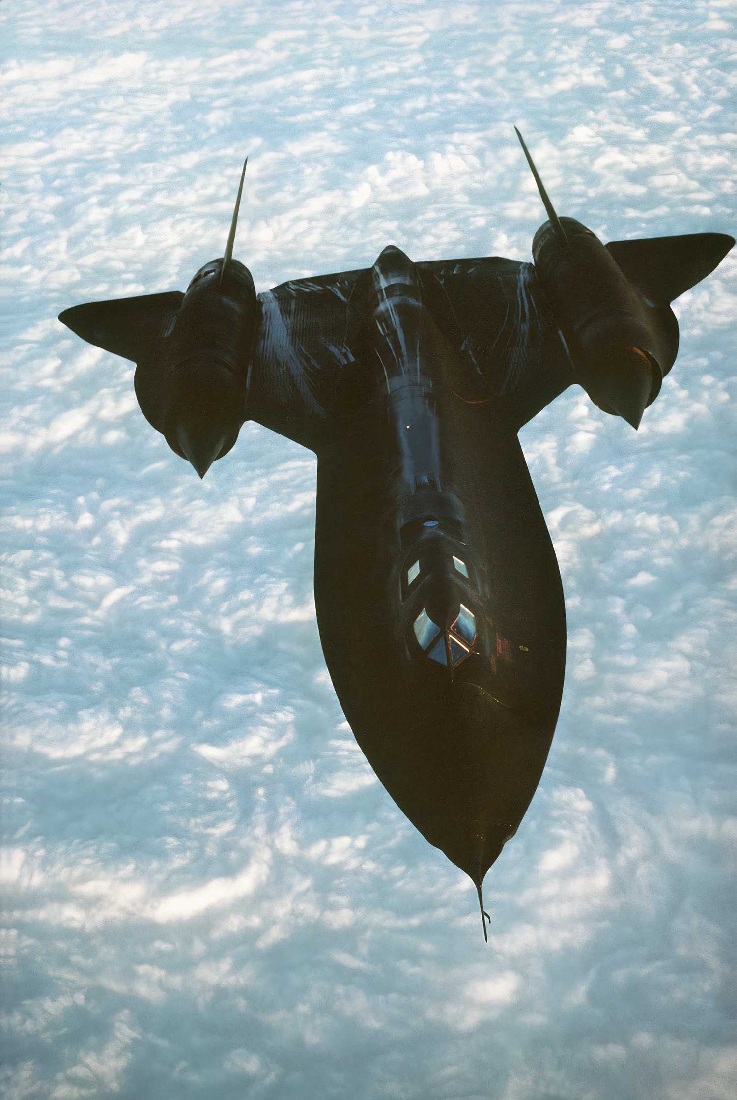 An SR-71 soars above wispy cloud formations below. 
