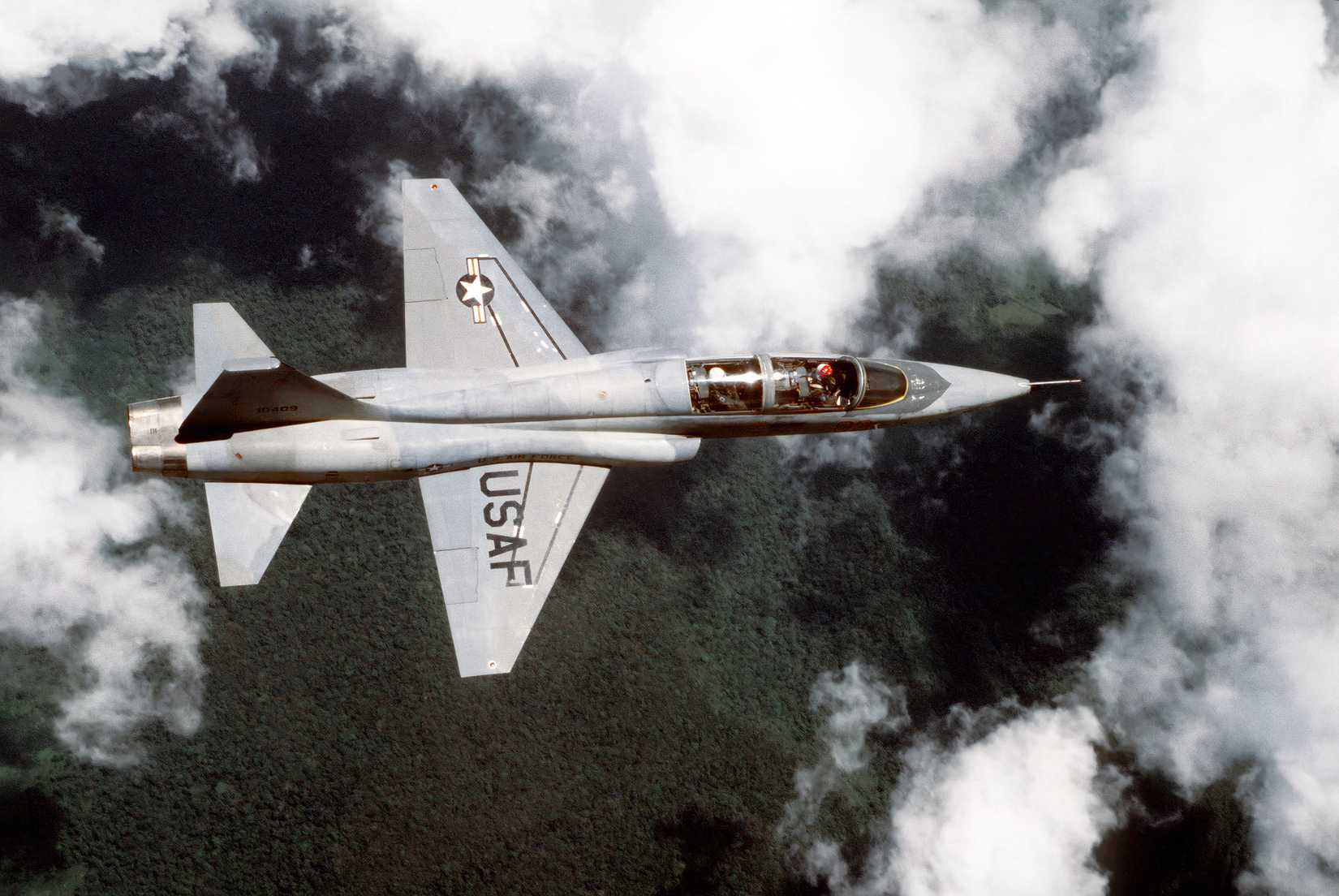 A photo showing the top view of a T-38 Talon training jet while flying above the clouds.