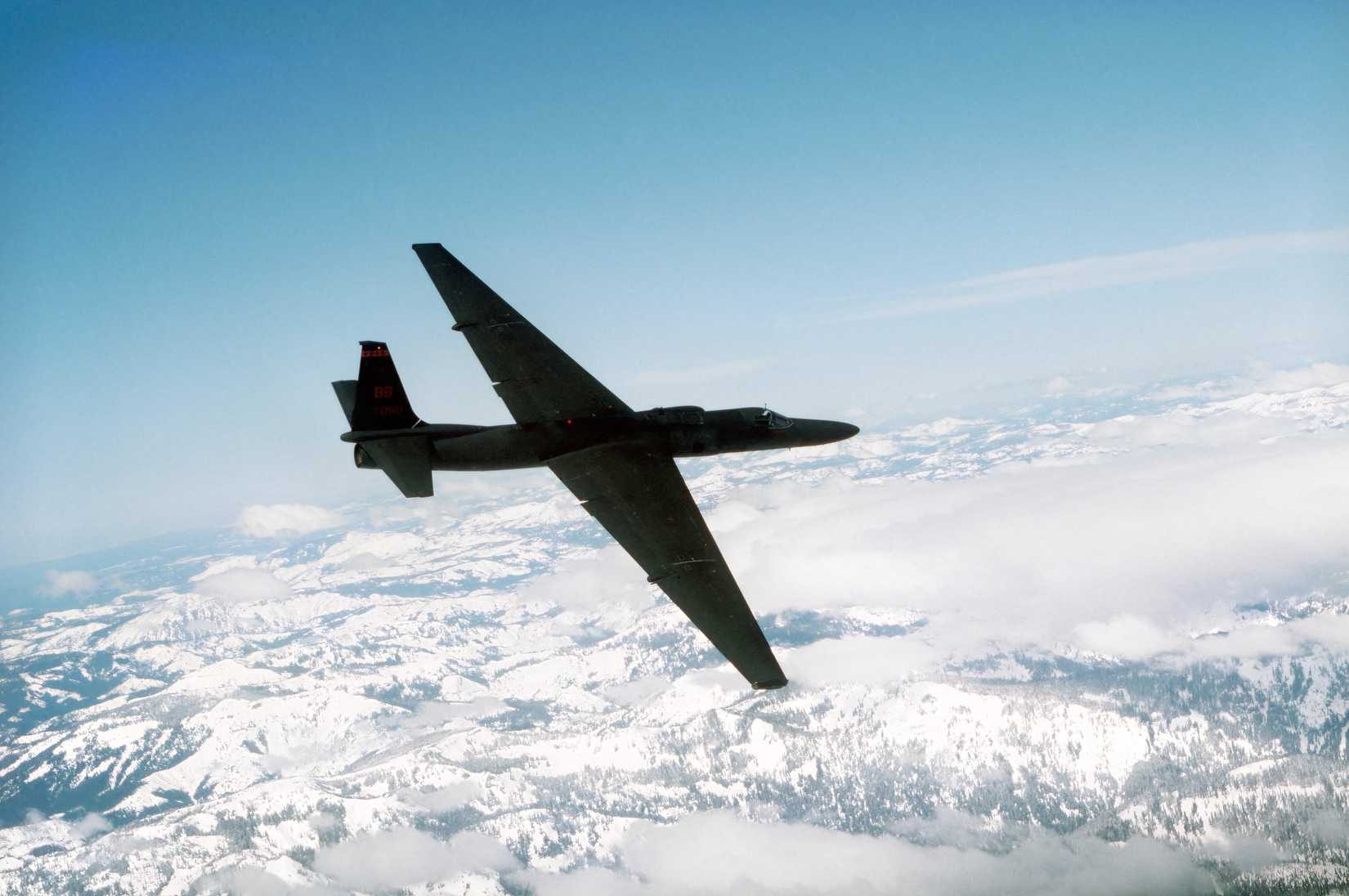 A photo of a U-2 Dragon Lady flying, with a snowcapped mountain range in the background. 