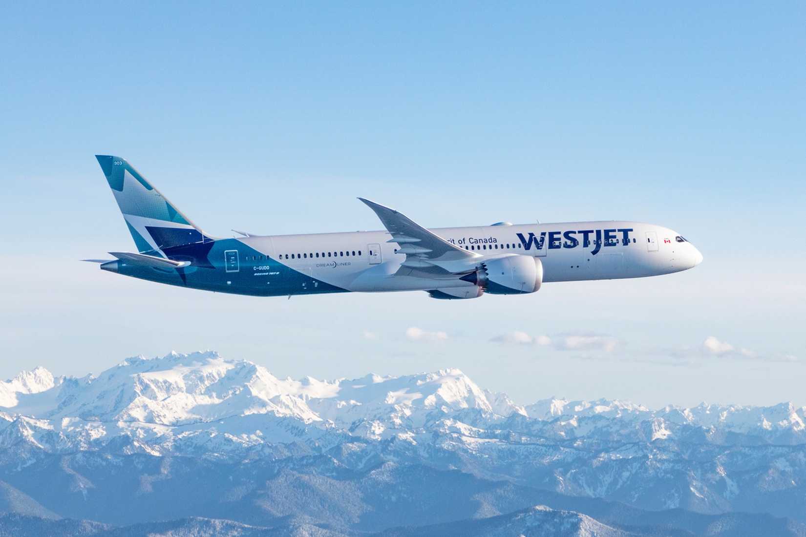 WestJet Boeing 787-9 flying over rocky mountains