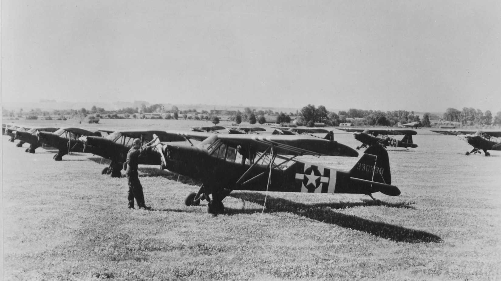 A lineup of Vultee L-5's and Piper L-4's somewhere in the ETO. These liaison and observation planes, %22The Grasshopper Fleet%22 have been assembled and test flown and are ready for delivery to front line units in France, or wherever they are needed