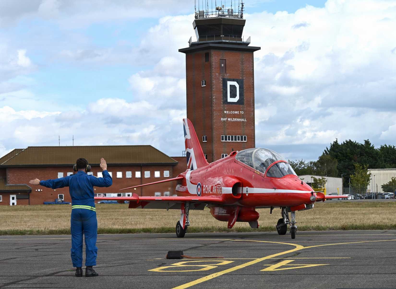 A member of the Royal Air Force Aerobatic Team’s travelling support crew, “Circus,” marshals a Hawk T1 aircraft into its parking spot at RAF Mildenhall