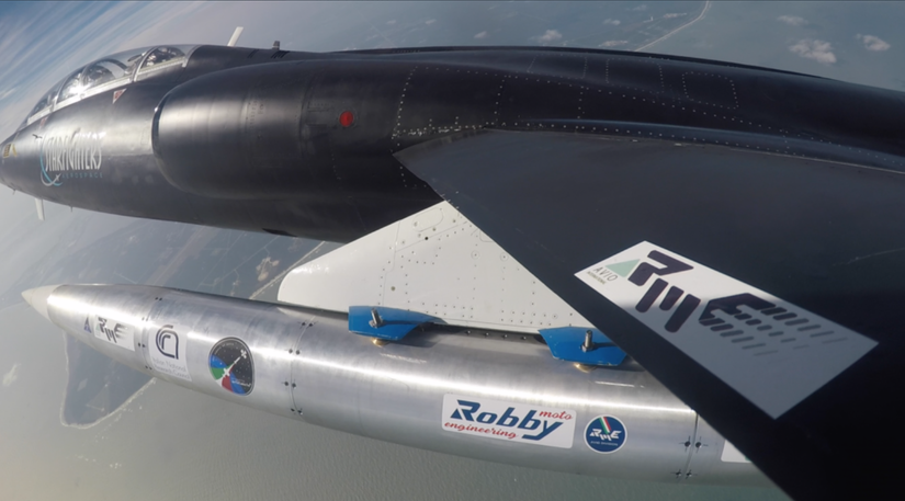 A test article under the TF-104G-M‘s left wing in flight as seen from a wingtip camera