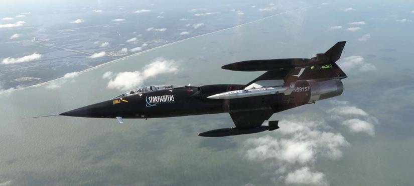 A test article under the TF-104G-M‘s left wing in flight