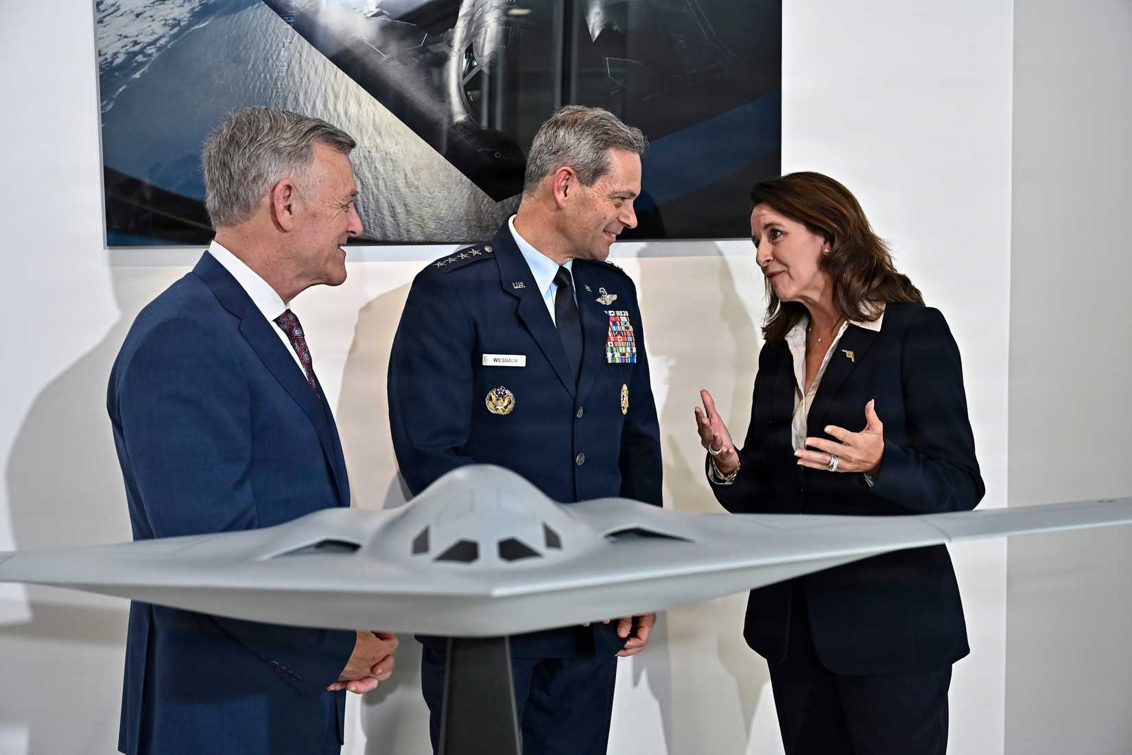 Air and Space Forces Association President Burt Field, left, Air Force Chief of Staff Gen. Ken Wilsbach and Northrup Grumman CEO Kathy Warden speak after posing behind a model of the B-21 Raider bomber