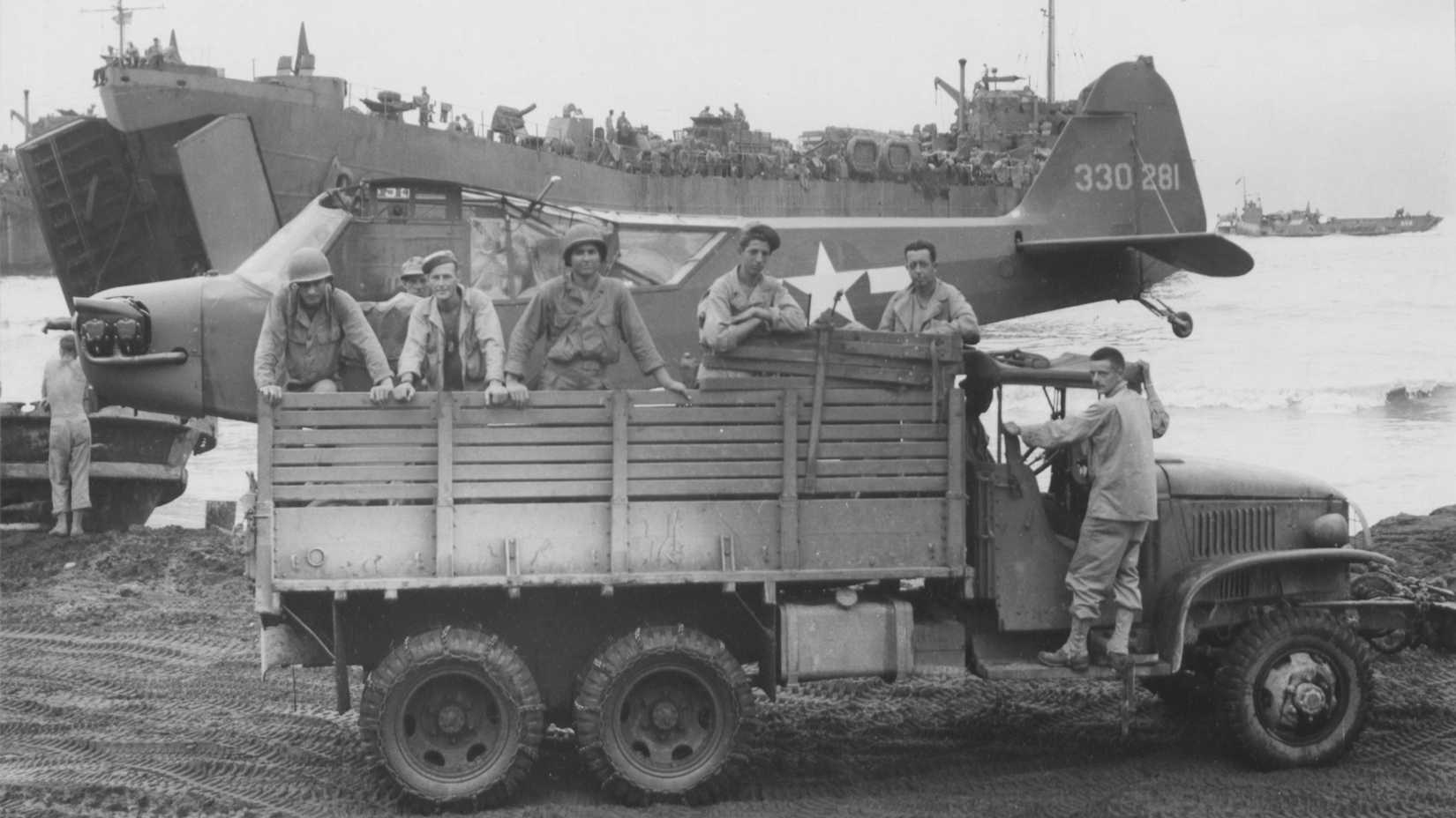 At Wakde Island, Dutch New Guinea, on 28 June 1944, a Piper L-4 is transported by truck to be loaded on a LST (Landing Ship Tank) prior to the invasion of Noemfoor Island which took place on 2 July 1944