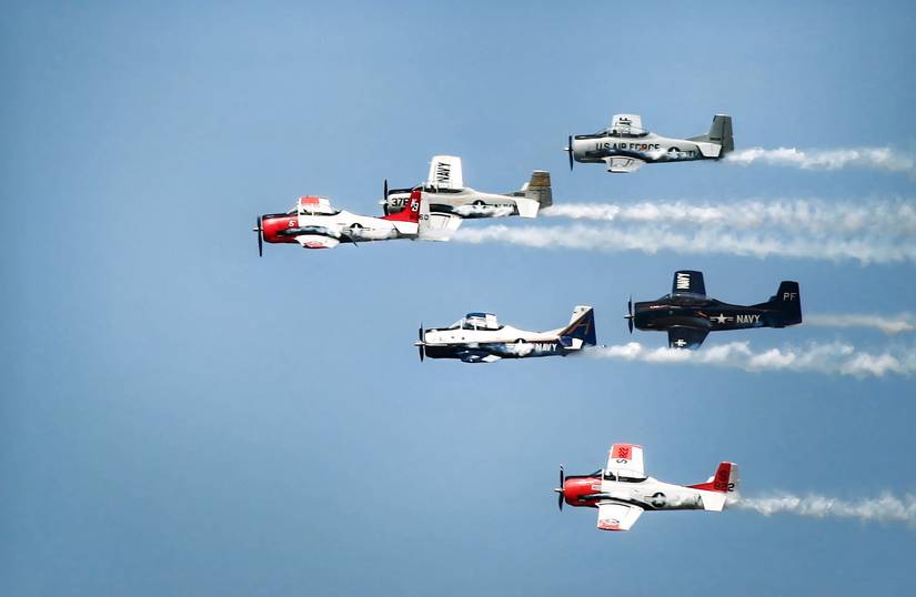 A photo of six historic World War Two aircraft flying in a tight formation at the EAA airshow.