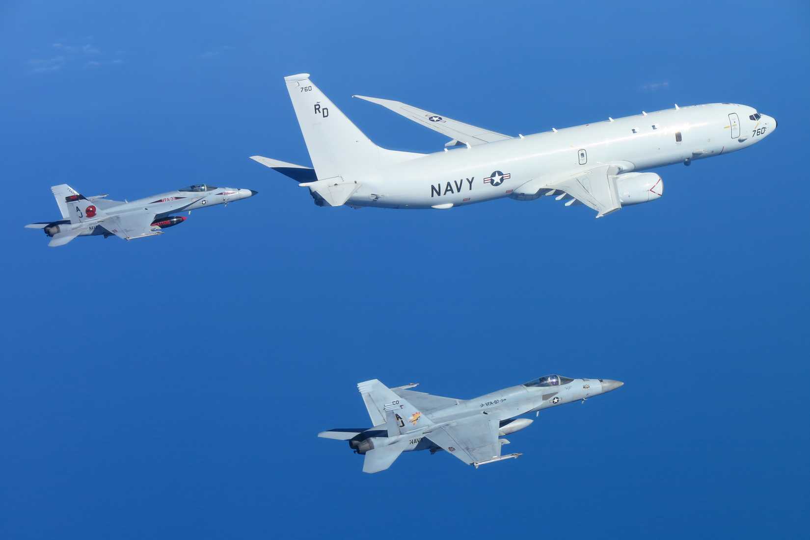 FA-18Es from VFA-31 Tomcatters and VFA-87 Golden Warriors intercept and escort a P-8A Poseidon maritime patrol aircraft, assigned to the Golden Swordsmen of Patrol Squadron (VP) 47