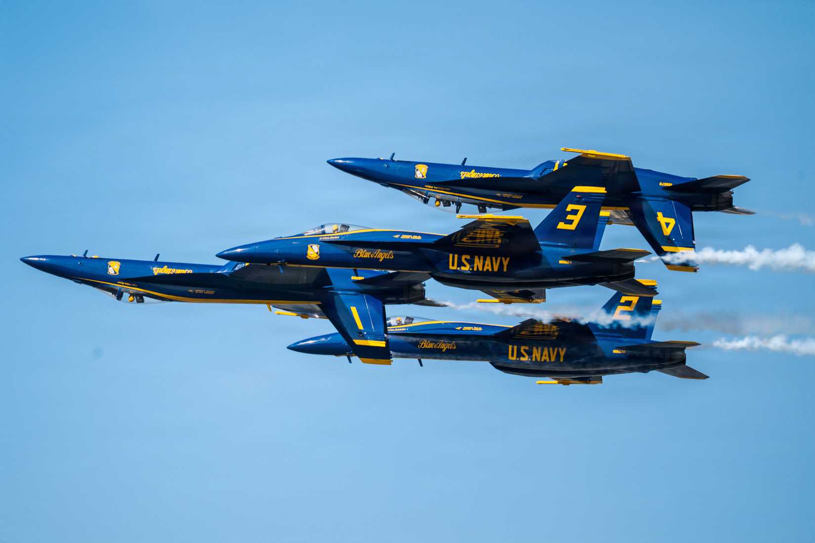 Four FA-18 Super Hornet aircraft with the US Navy flight demonstration squadron, the Blue Angels, execute a formation maneuver with two aircraft inverted