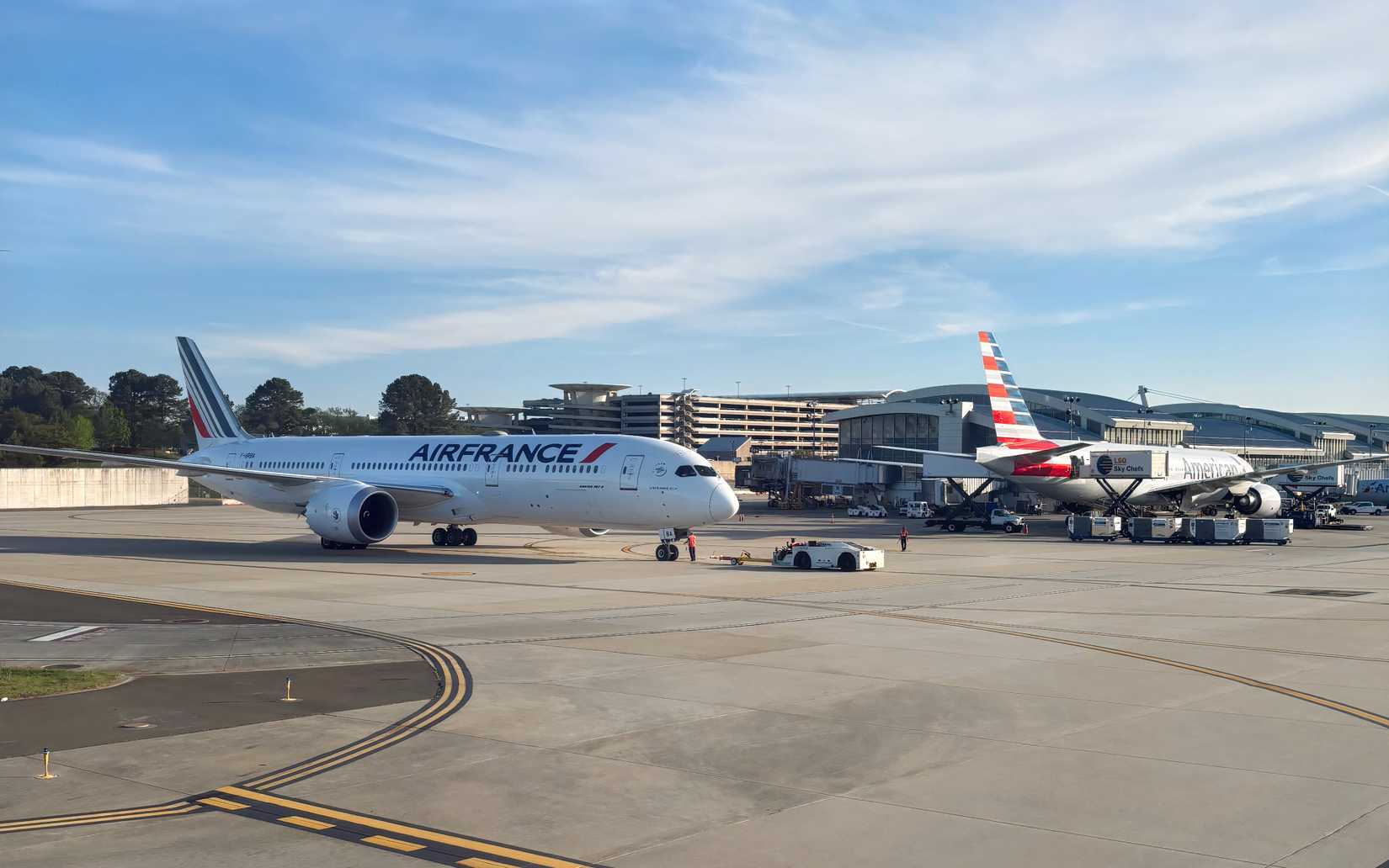 An Air France 787 pushing back in front of an American Airlines 777