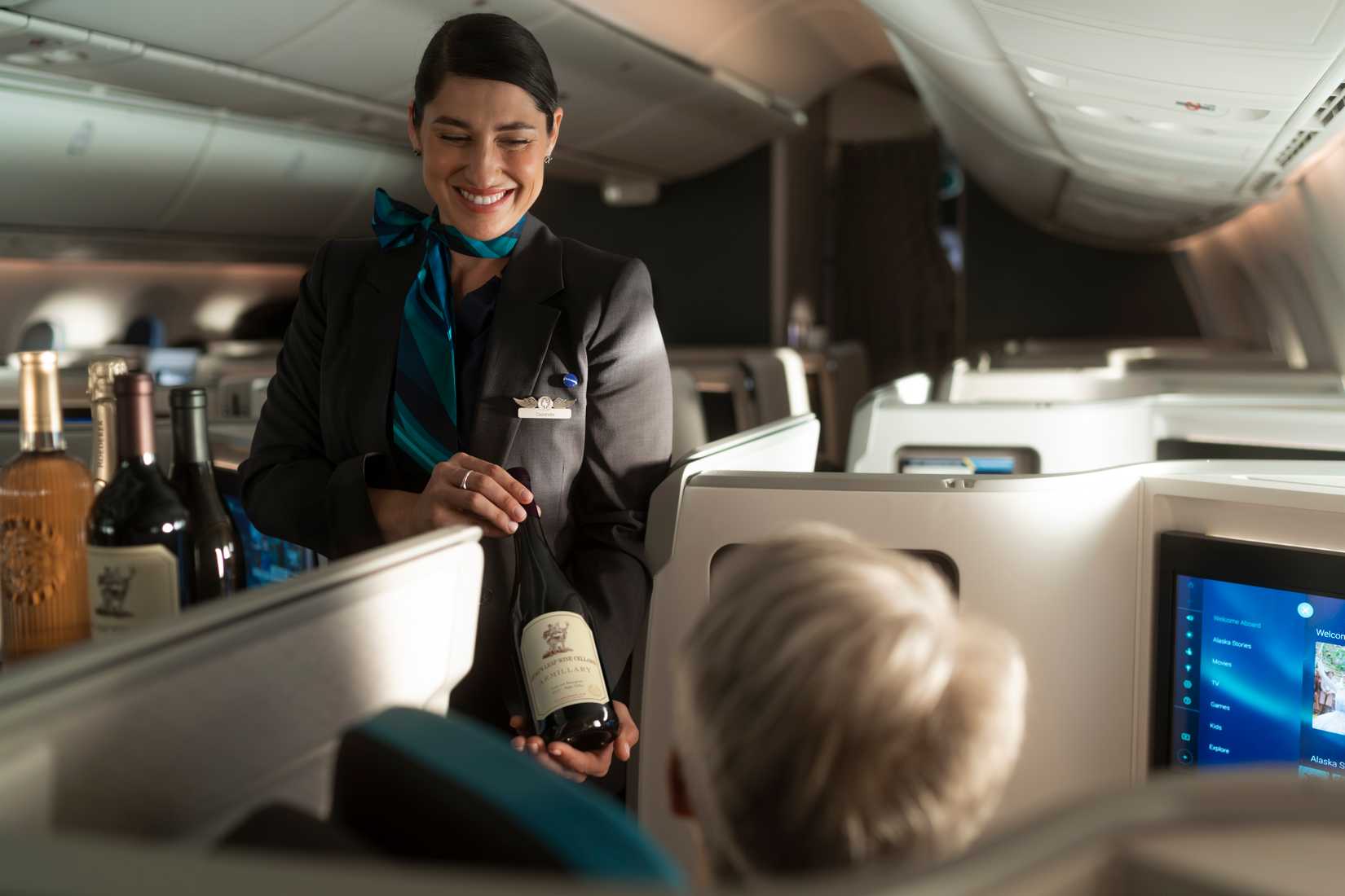 A flight attendant serves wine