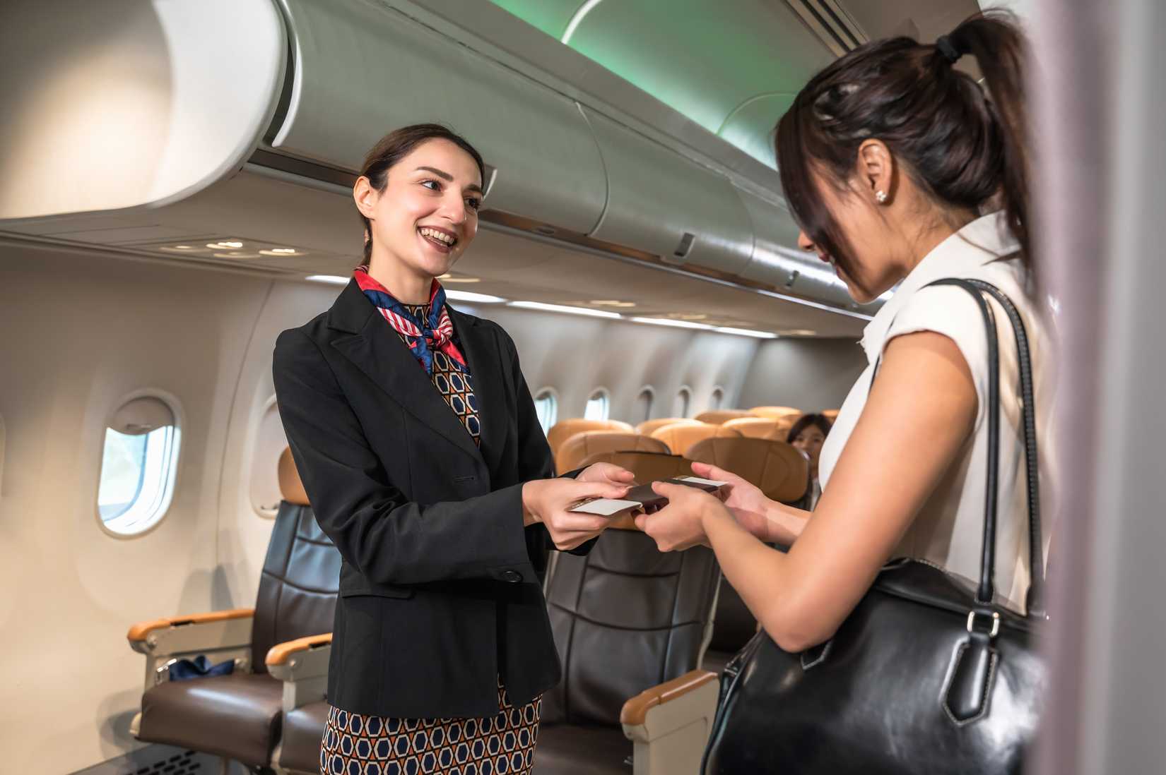 passenger boarding aircraft greeted by flight attendant