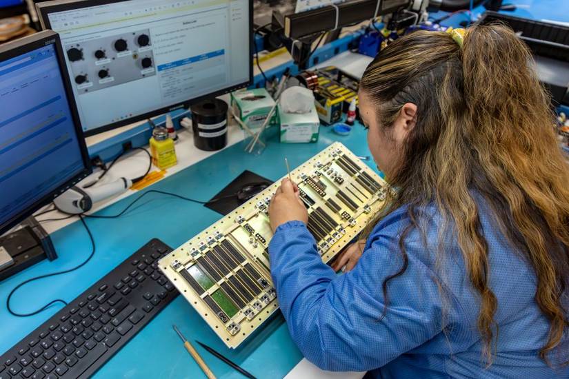 Skilled technicians at Northrop Grumman’s CNI lab closely inspect F-35 components, alongside advanced robotics.