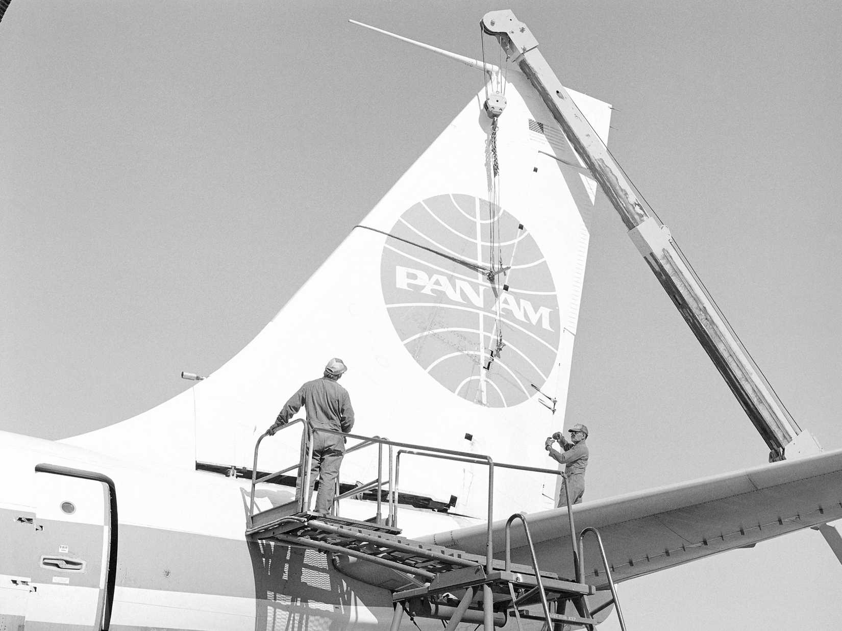 Technicians discuss the next step prior to lowering the vertical stabilizer of a Boeing 707 aircraft