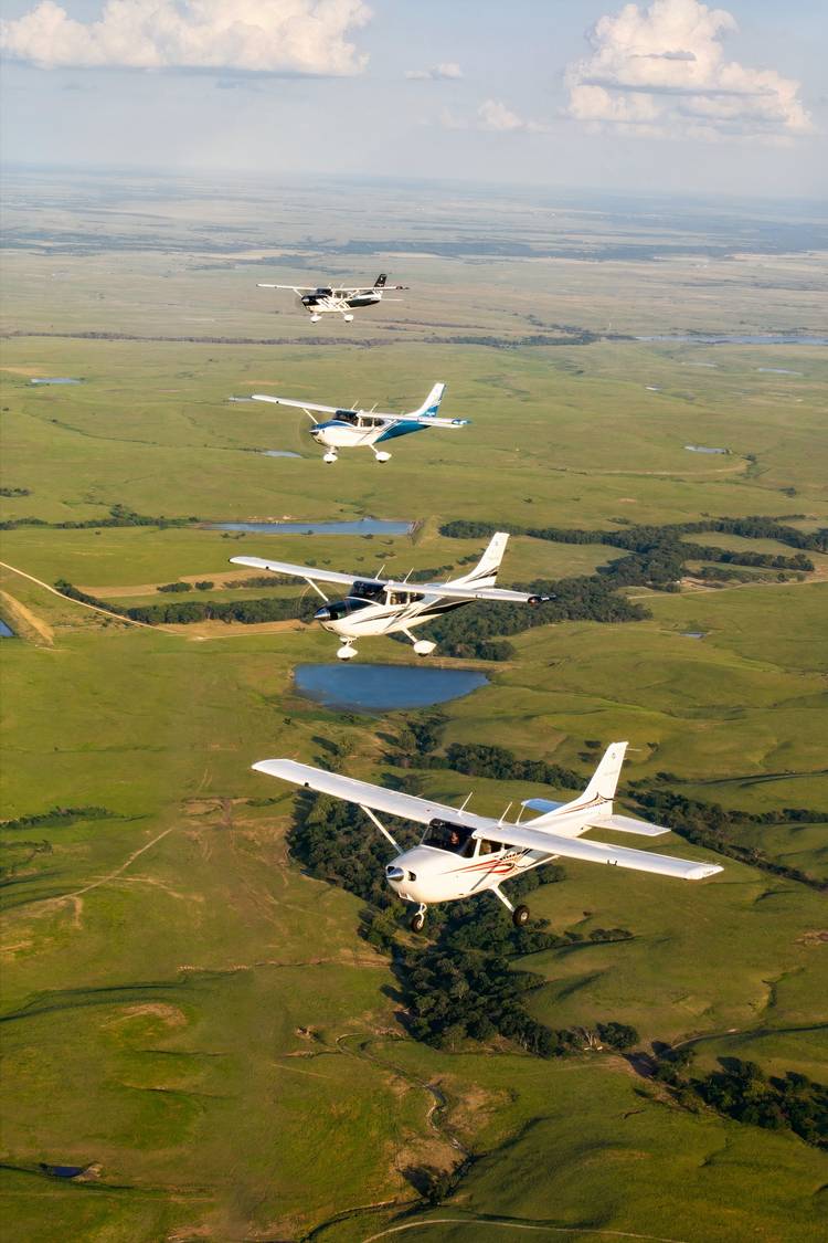 A photo showing four Cessna 172s flying in close formation over a green countryside.