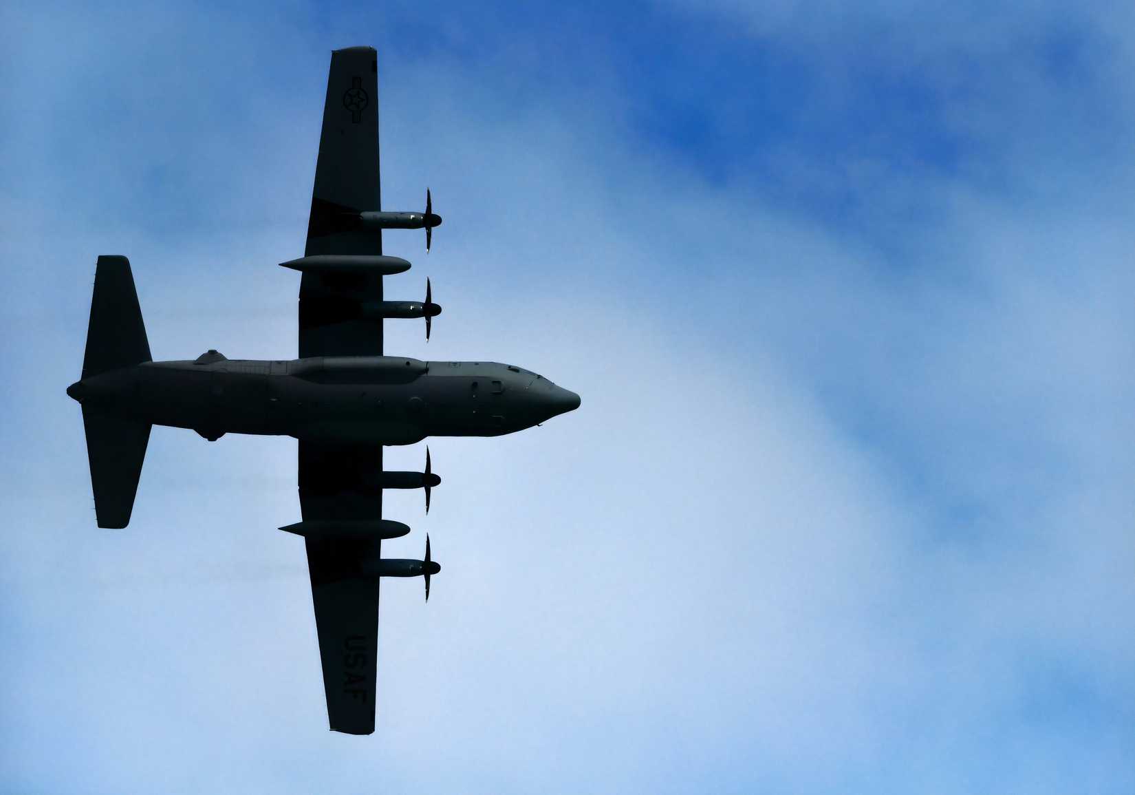 A photo showing the under side of a C-130H as it flies over head. 